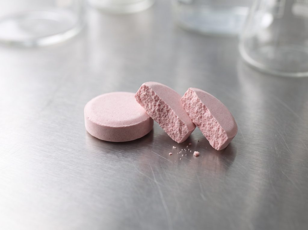 Pink chewable supplement tablets showing the compressed texture and easy-to-chew format.