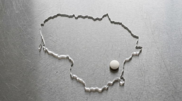 Outline of Lithuania on a stainless steel surface with a pharmaceutical tablet, representing the country's life sciences manufacturing industry – Noviatic.